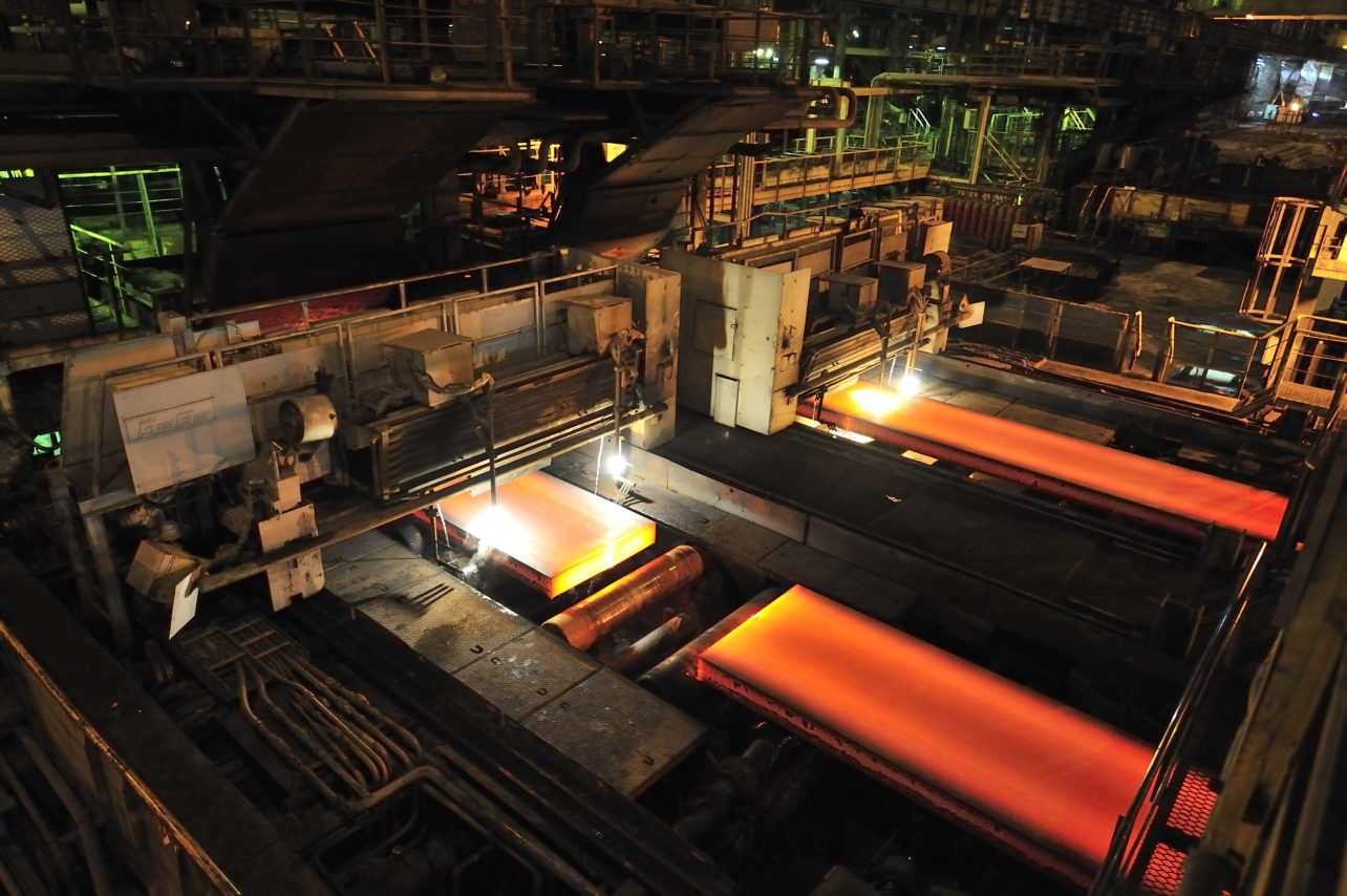 Continuous cast steel in steel mill leaving furnace and being cut.