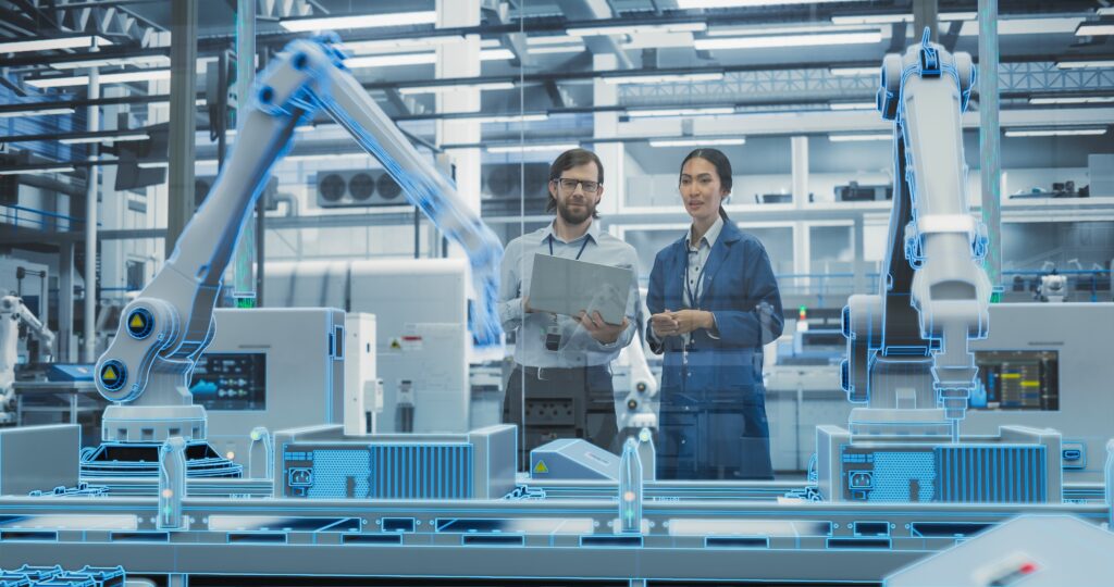 Two engineers stand in a high-tech smart factory using agentic AI to monitor and optimize robotic systems. One holds a laptop while the other observes a production line surrounded by holographic overlays and robotic arms, symbolizing intelligent automation and real-time decision-making powered by agentic AI.